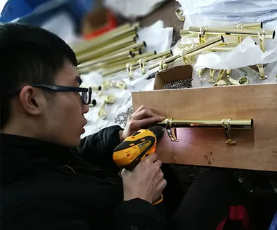 Worker assembling a coffin handle with a power screwdriver at the Virtue Hardware factory